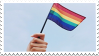 a stamp with a hand holding a rainbow flag on a bright blue sky background